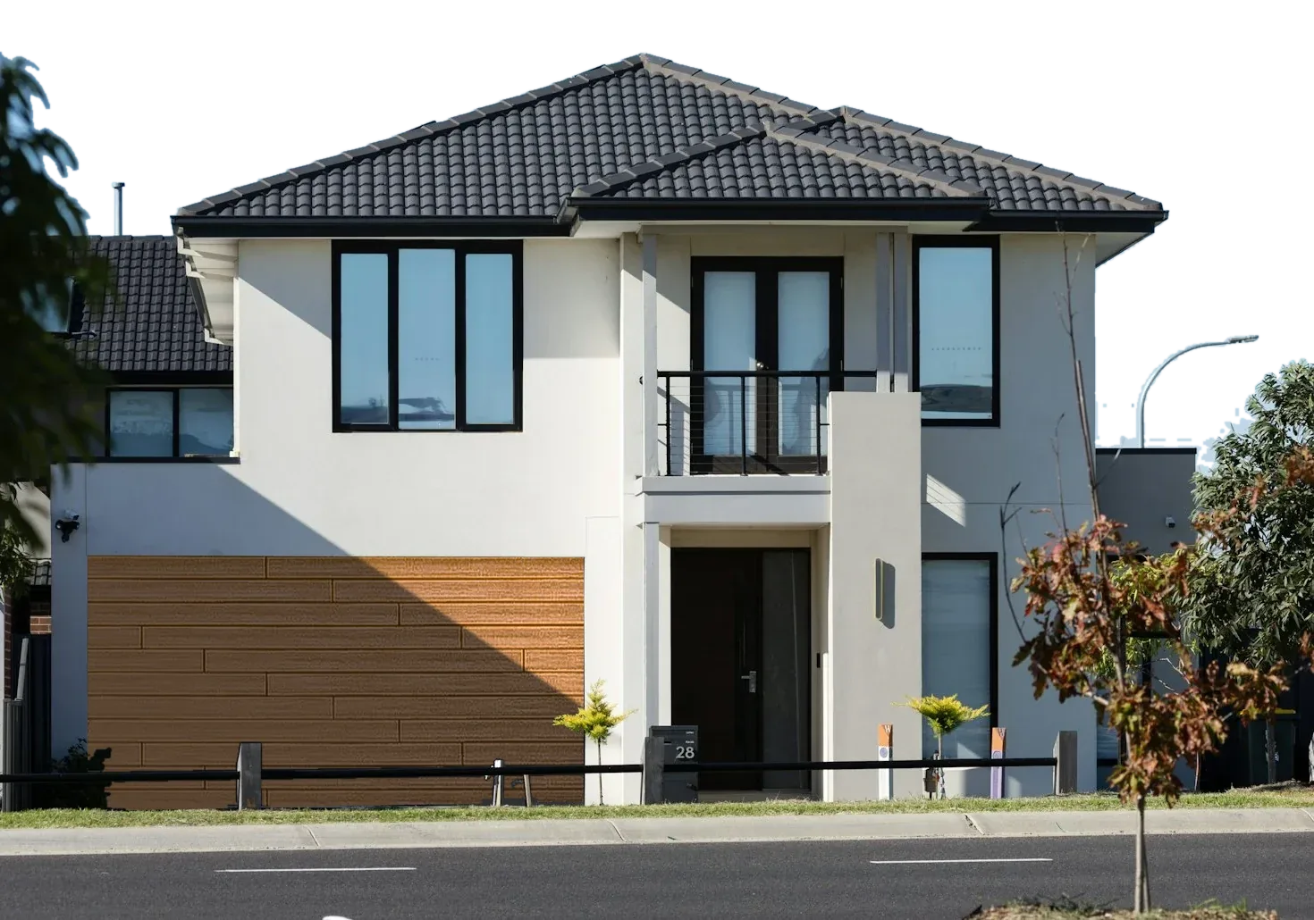 A modern two-storey rendered home with a horizontal cedar garage door, standing against the sky